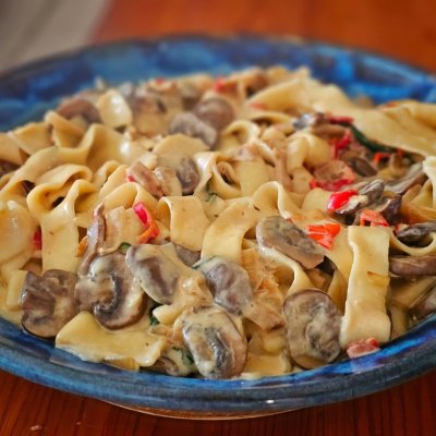 Scratch made tagliatelle pasta in a mushroom and caramelized onion cream sauce with some sweet red peppers and spinach.