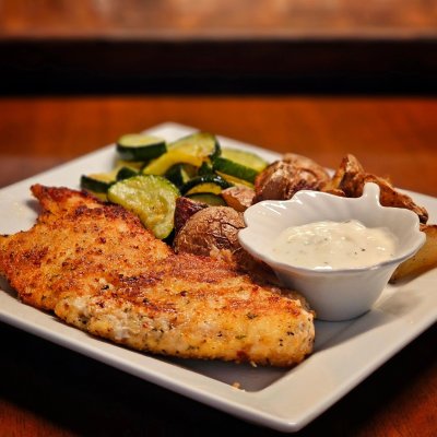 Crispy breaded chicken with roasted potatoes, zucchini, and a yogurt dip.